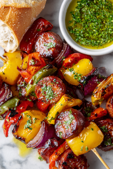 Receta de brochetas de salchichas a la parrilla, perfectas para reuniones familiares y barbacoas, con chorizo y verduras frescas.